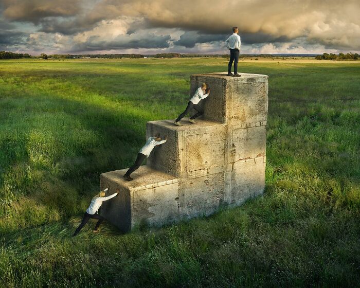 A man climbs and stands on giant concrete steps in a field, showcasing surreal photo manipulation by Erik Johansson.