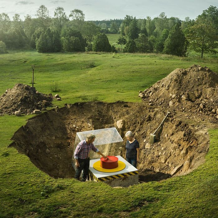 A mind-bending photo manipulation showing two people uncovering a giant red button buried in a green landscape.