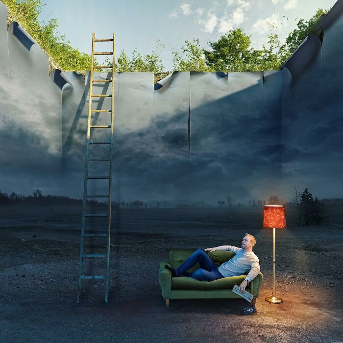 A man on a couch gazes up at a surreal ladder extending to a sky-like ceiling in a photo manipulation by Erik Johansson.