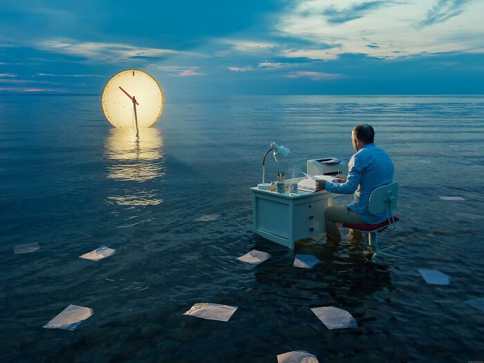 Man at desk on water with giant clock, showcasing Erik Johansson's photo manipulations.