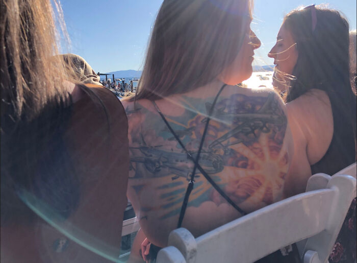 A vibrant tattoo of the B-29 Superfortress on a woman's back at an outdoor event in sunlight. A vibrant tattoo of the B-29 Superfortress on a woman's back at an outdoor event in sunlight.