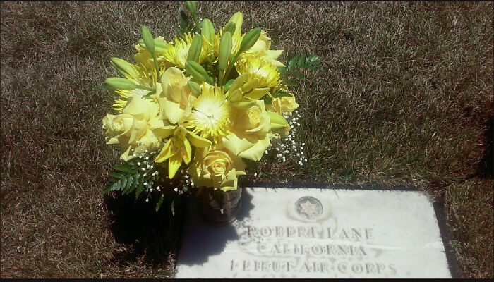 Yellow flowers on a grave marker, symbolizing connection and remembrance, related to B-29 Superfortress tattoo story. Yellow flowers on a grave marker, symbolizing connection and remembrance, related to B-29 Superfortress tattoo story.