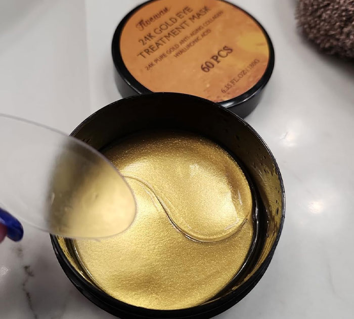 Woman smiling with under-eye and forehead gold patches, a cheerful and cheap Mother's Day gift idea.