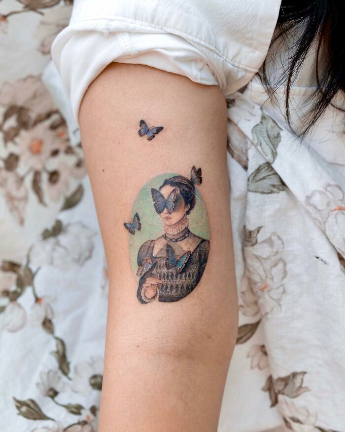 Realistic tattoo featuring a vintage portrait with butterflies on an arm, showcasing artistic detail.
