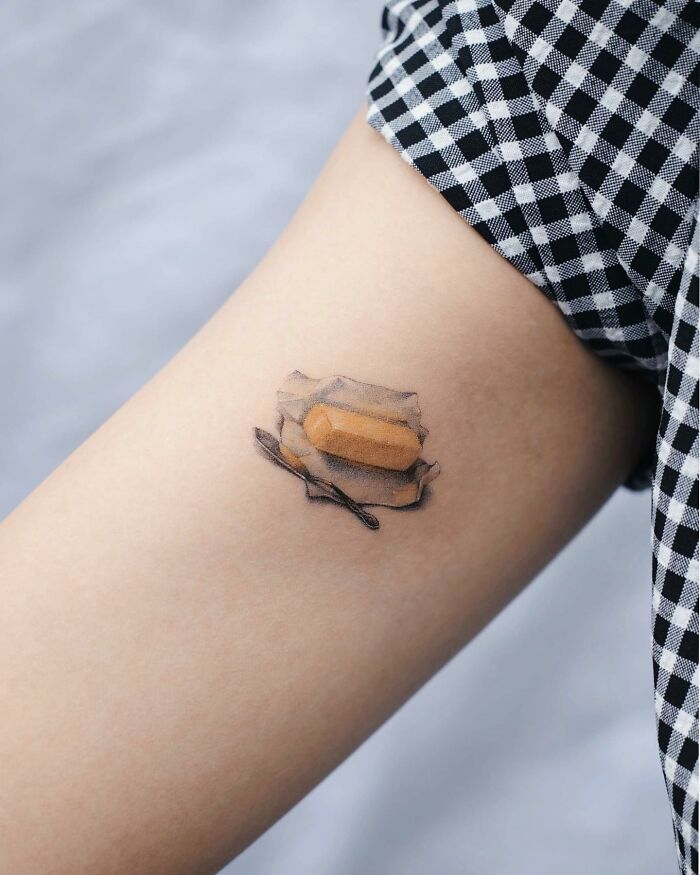 Realistic tattoo of a butter pat on skin, showcasing tattoo artistry and precision in design.