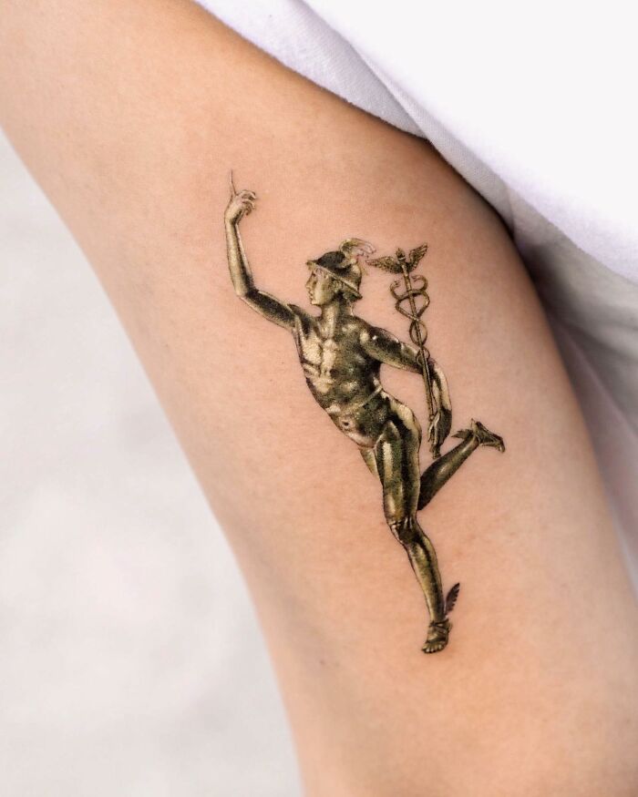 Realistic tattoo of a detailed figure on an arm, showcasing the artist's intricate work.