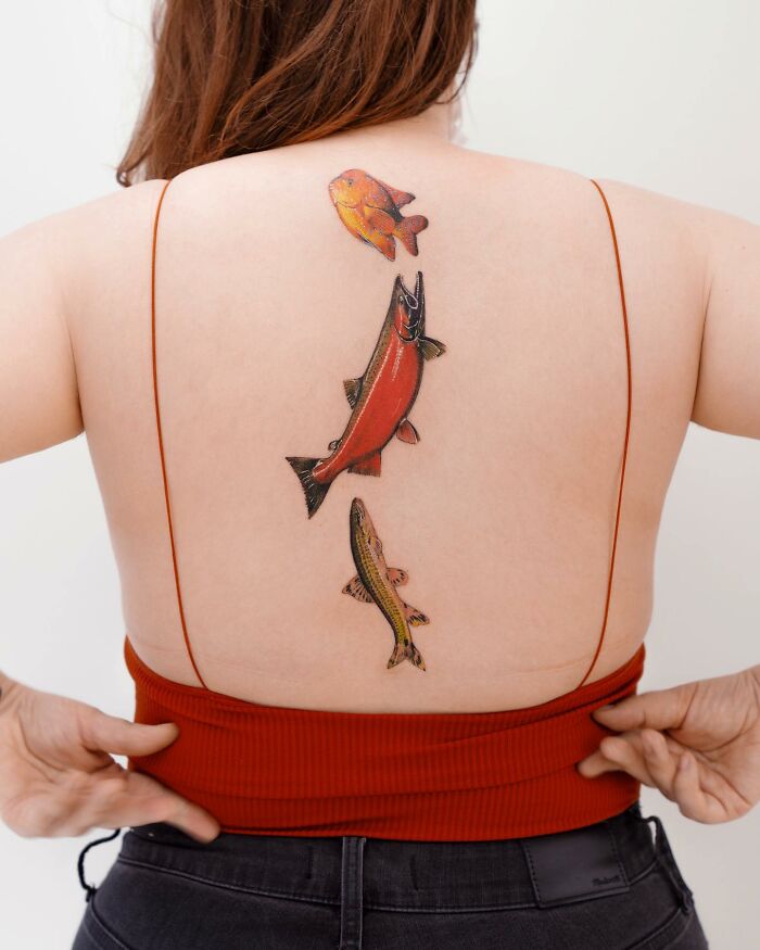 Realistic tattoo of three fish on a person's back, showcasing flawless detail and artistry.