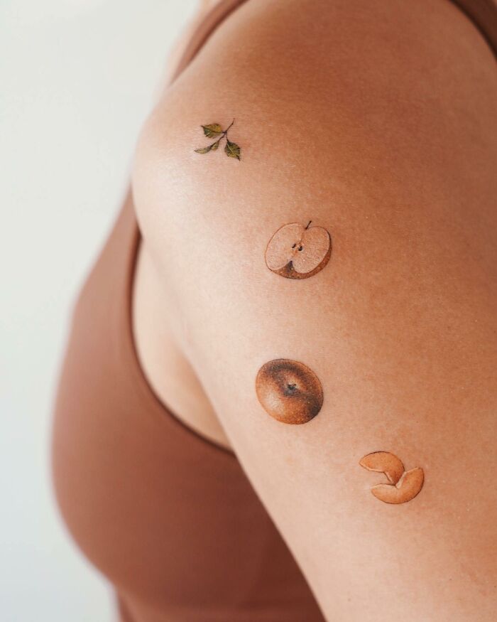Realistic tattoos of fruit and leaves on a person's arm, showcasing remarkable artistry.