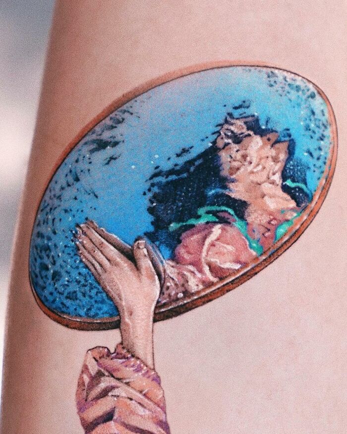 Realistic tattoo depicting a person gazing into a reflective surface, showcasing intricate detail and vivid colors.