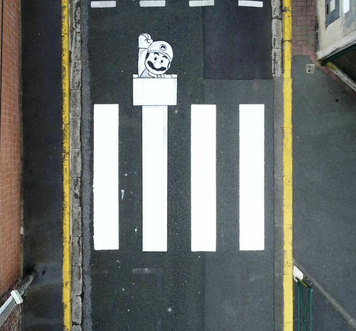 "Humorous street art with character peeking over crosswalk, creatively integrated by Oakoak."