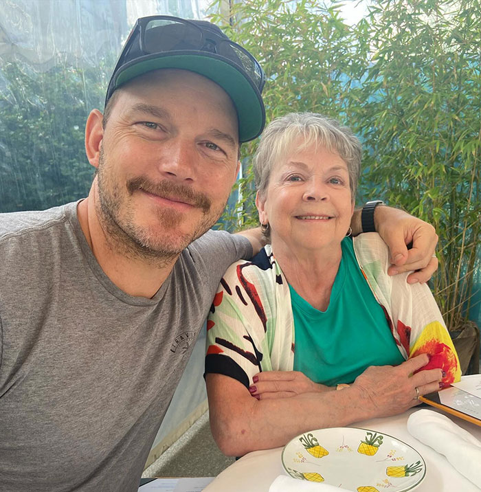 Chris Pratt smiling with a woman, stirring controversy with Mother&rsquo;s Day post at a casual outdoor setting.