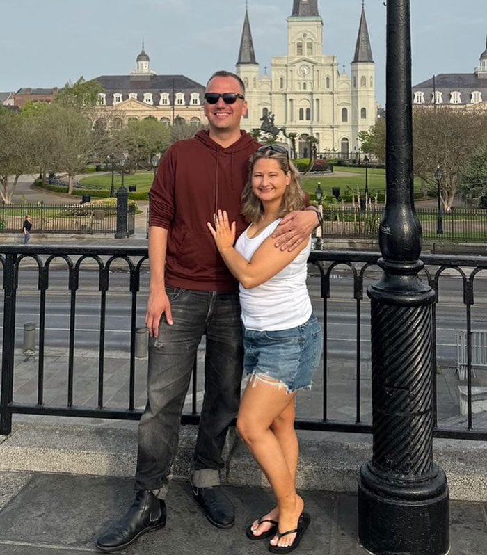 Couple smiles in front of a historic building, embracing positivity and moving beyond past challenges.
