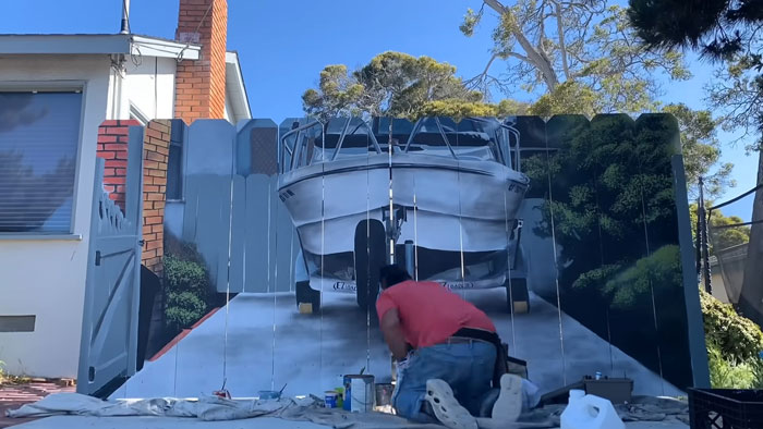 City Forces Guy To Build A Fence To Hide His Boat, He Complies Maliciously And Paints A Mural On It