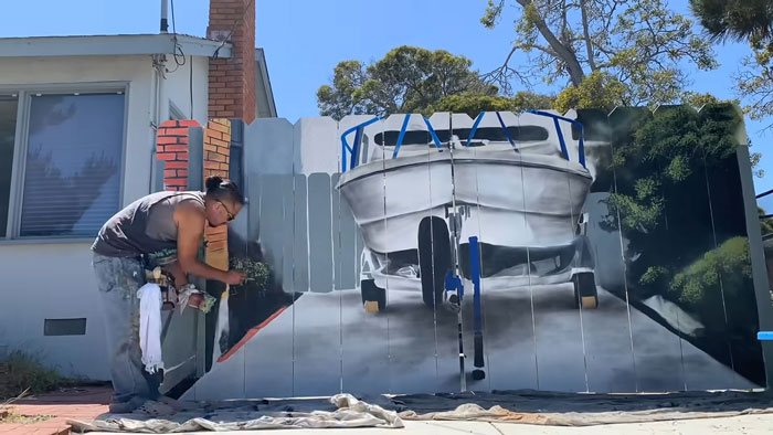 City Forces Guy To Build A Fence To Hide His Boat, He Complies Maliciously And Paints A Mural On It