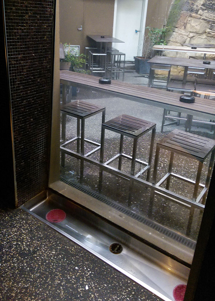 Modern bar seating area with wooden stools and tables, showcasing innovative design ideas in bars and restaurants.