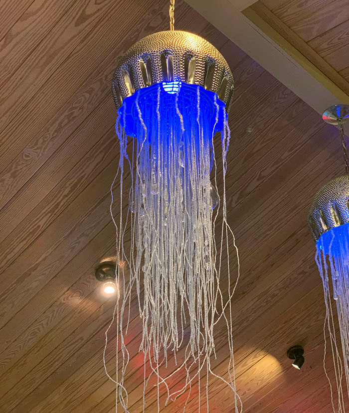 Jellyfish-shaped hanging light fixture with blue glow in a bar showcasing brilliant restaurant design ideas.