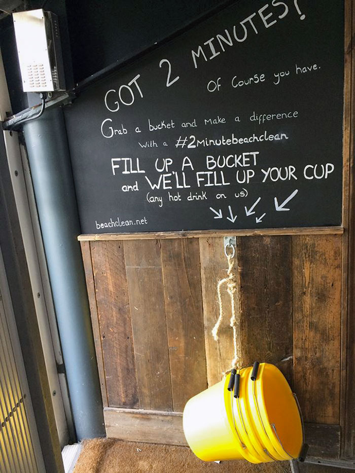 Chalkboard in a bar promoting a bucket cleanup challenge with free hot drinks, showcasing brilliant bars and restaurants ideas.
