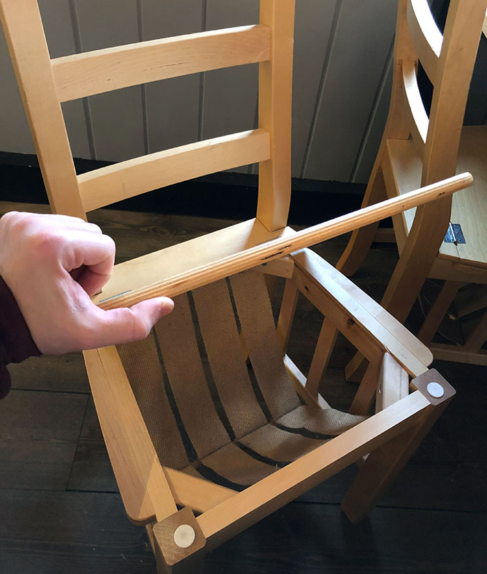 Hand holding a wooden chair slat above a disassembled chair frame in a bars and restaurants setting with brilliant ideas.