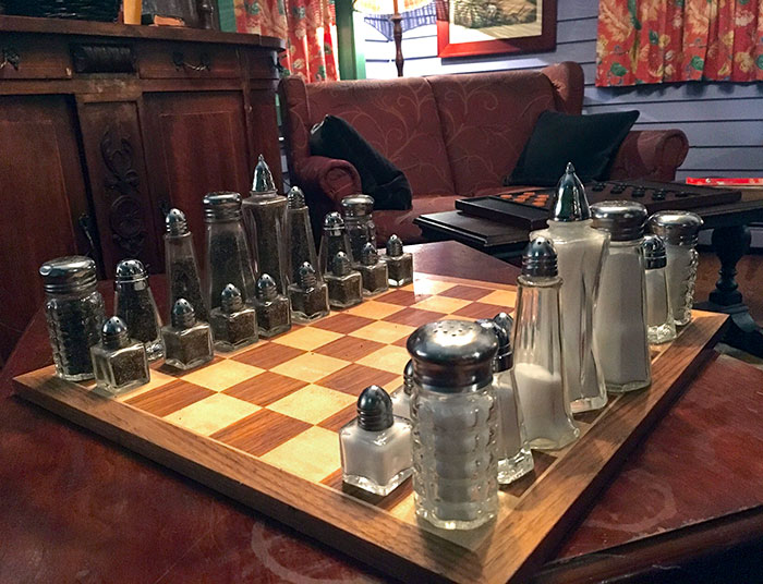 Chess board with salt and pepper shakers as pieces, showcasing a brilliant idea in bars and restaurants interior design.
