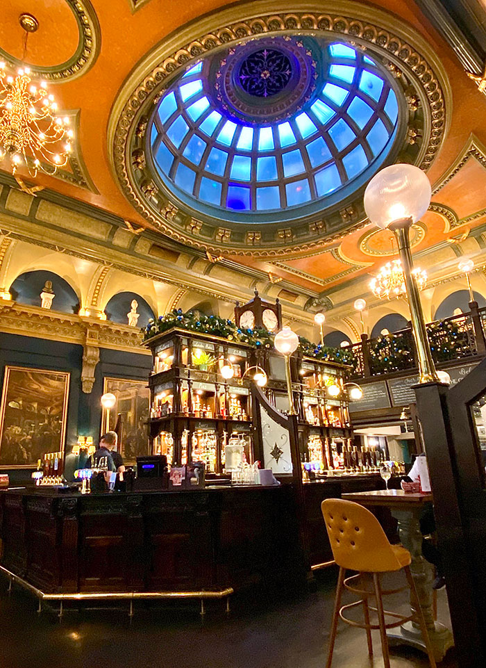 Ornate bar interior with a glowing dome ceiling, chandeliers, and elegant vintage decor in a top bars and restaurants setting.