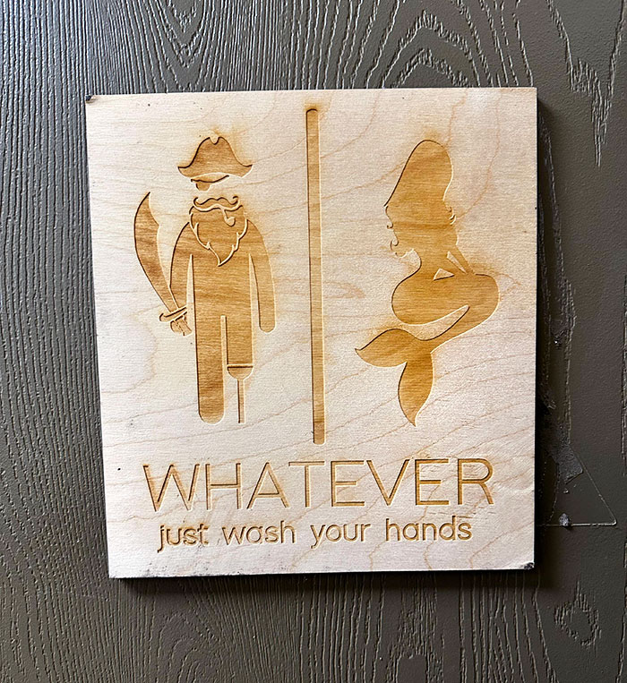 Creative restroom sign at a bar featuring pirate and mermaid icons with a humorous handwashing reminder.