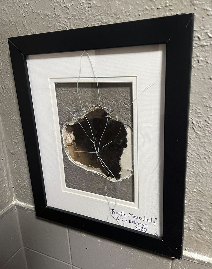 Framed wall art of broken glass titled Fragile Masculinity inside a bar or restaurant with creative decor ideas.