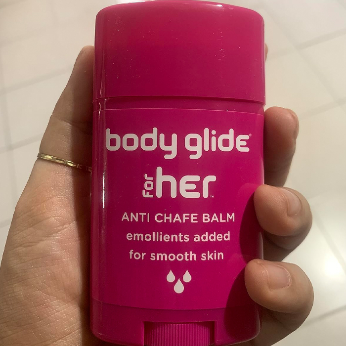 Hand holding a pink anti-chafe balm, ideal for travel light and smart packing.