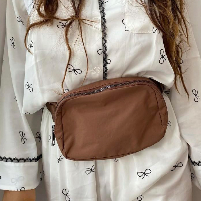 Brown f***y pack on a person wearing a patterned white shirt, ideal for traveling light and smart.