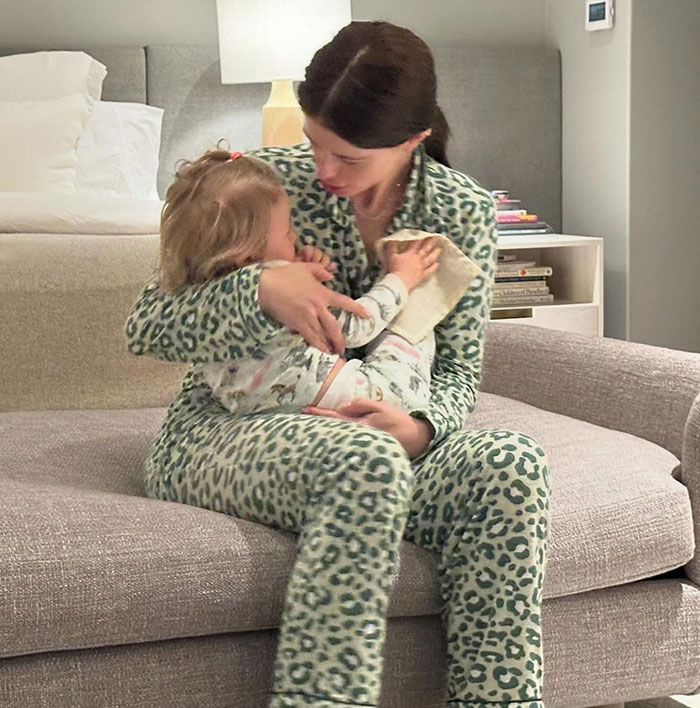 Mother holding child on sofa, wearing leopard print pajamas, related to Chris Pratt controversy.