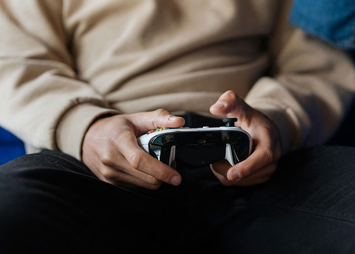 Person holding a video game controller, focusing intently on their gameplay session.