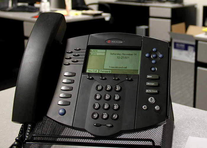 Office desk phone with digital screen displaying missed calls in a workplace setting.