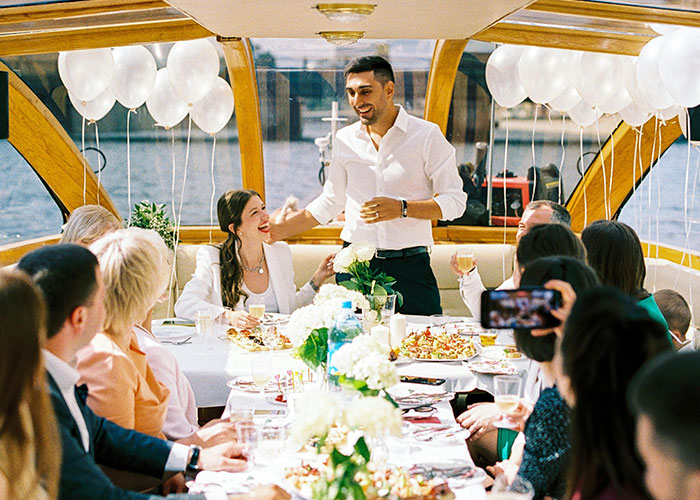 People gathered on a boat, celebrating, with white balloons and a buffet, capturing a joyful moment together.