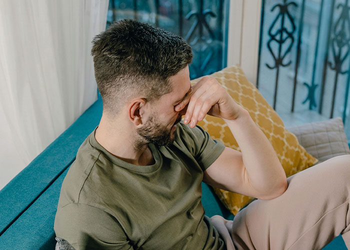 Man sitting on a couch, covering his face, reflecting on a cringe-worthy experience.