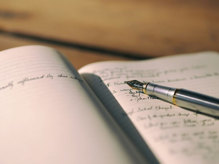 Open notebook with handwritten notes and a fountain pen resting on pages, symbolizing frugal wins and saving money.