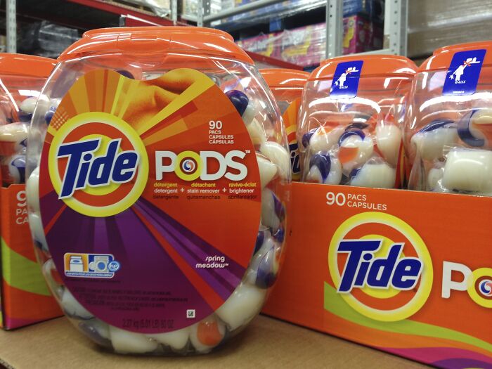 Containers of Tide PODS detergent capsules on store shelves, illustrating frugal money saving tips.