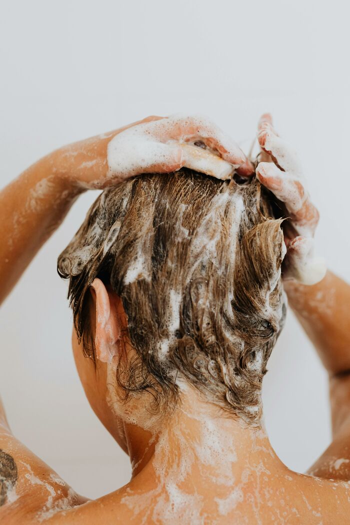 Person washing hair with soap lather, demonstrating a frugal win for saving money on personal care.