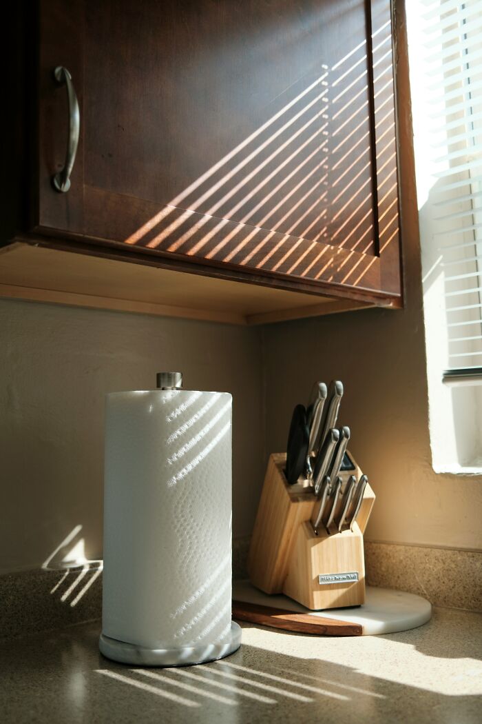 Sunlight casting striped shadows on kitchen cabinet, paper towel, and knife block representing frugal wins for saving money.