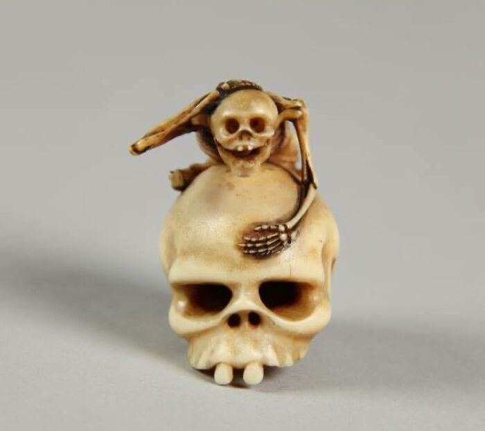 Carved Ivory Japanese Netsuke Depicting A Human Skeleton Posing On A Large Human Skull, C. 1750-1850