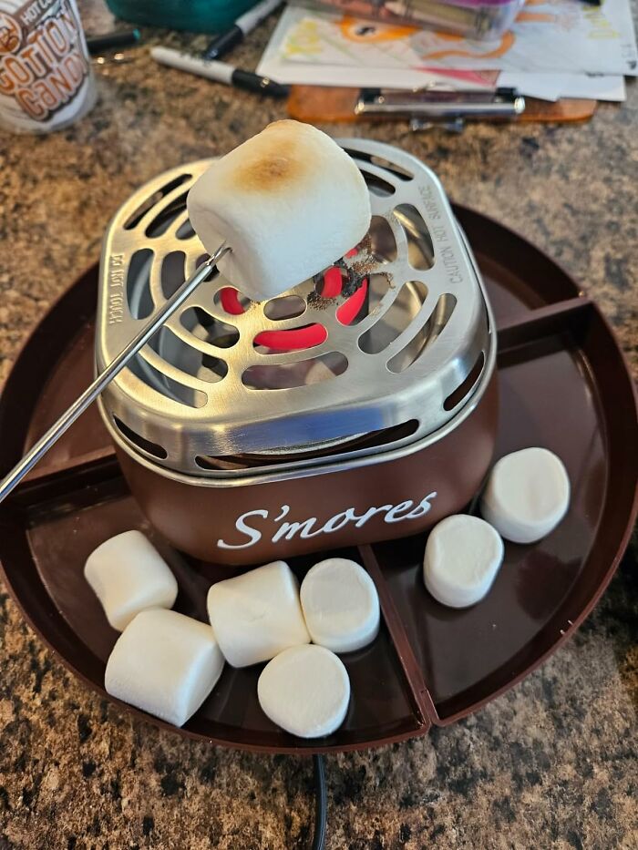 Compact s'mores maker with marshmallows being toasted on a metal grill, showcasing a clever random genius gadget.