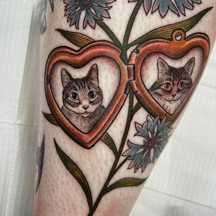 Cute pet portrait tattoos of cats in heart-shaped lockets with floral designs on skin.