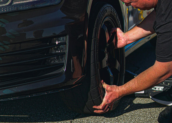 Person changing a car tire by hand on a black vehicle, illustrating unlikely events people experienced and improbable actions.