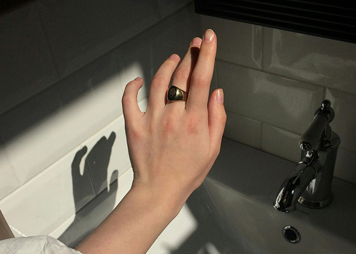 Hand with a ring casting an unusual shadow over a sink, illustrating improbable events that people have experienced.