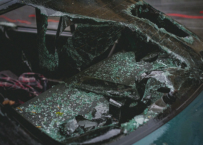 Shattered car windshield with broken glass scattered inside, showing an unlikely event people experienced.