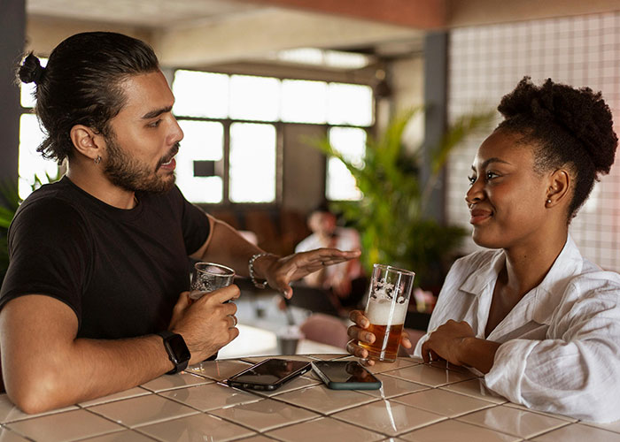 Two people sharing unlikely events experiences over drinks at a bar, illustrating improbable moments in real life.