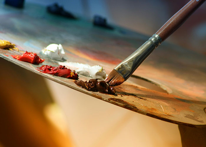 Close-up of an artist’s paintbrush mixing colors on a palette, illustrating unlikely events people experienced.