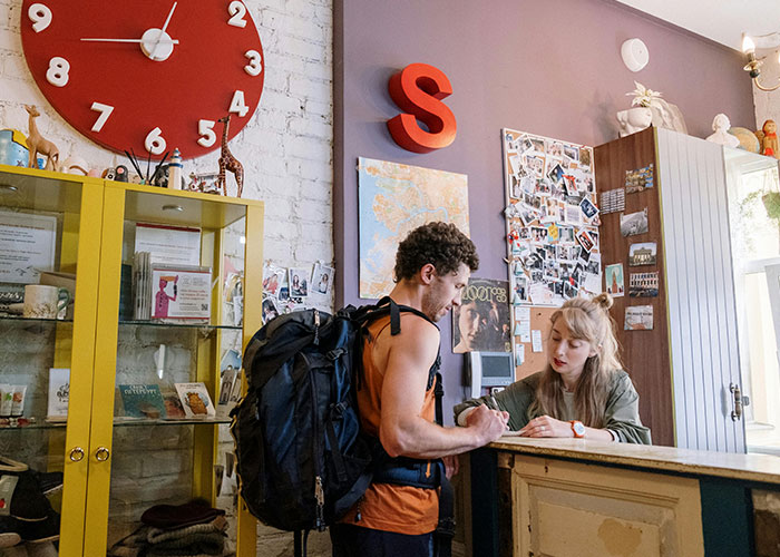 A traveler with a backpack checking in at a hostel reception, illustrating unlikely events people experienced during their journey.