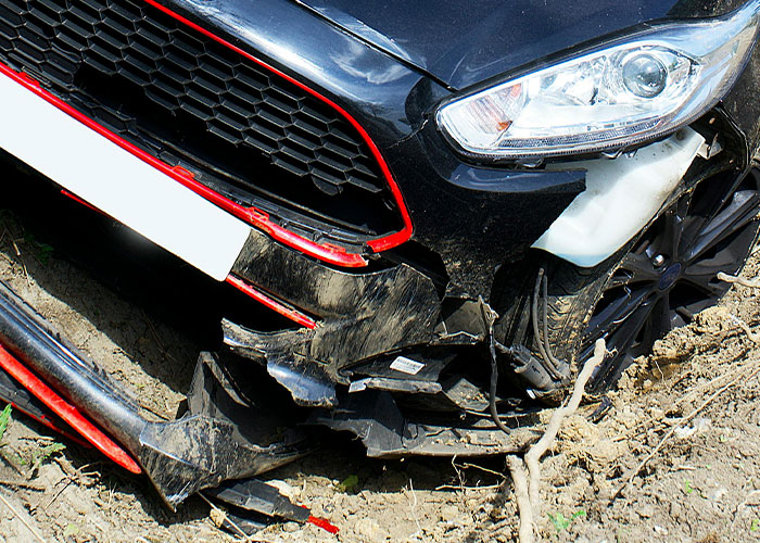 Damaged black car with broken front bumper and dirt, illustrating improbable but unlikely events people experienced.