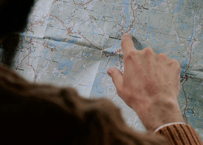 Person pointing at a detailed map, illustrating improbable events and unlikely experiences in exploration and travel.