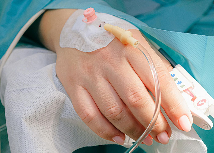 Close-up of a patient's hand with an IV line, highlighting unlikely events people experienced in medical situations.