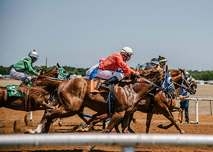 Horse race with jockeys competing closely on a dirt track, illustrating unlikely events and improbable moments experienced by people.